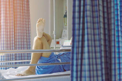 Low section of man relaxing on bed at home