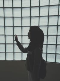 Side view of young woman standing against wall