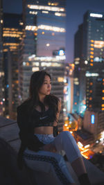Young woman looking at illuminated city at night