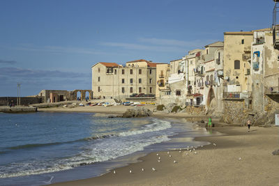 Buildings by sea against sky in city