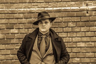 Portrait of man standing against brick wall