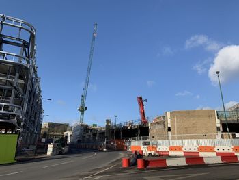 Vehicles on road by buildings against sky in city