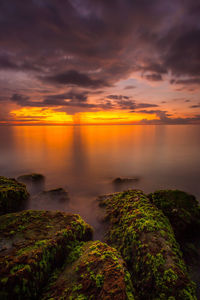 Scenic view of sea against dramatic sky during sunset