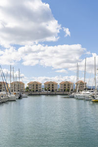 Sailboats in harbor against sky