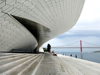 View of building entrance and bridge against cloudy sky