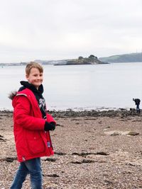 Portrait of boy standing on beach against sky