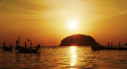 Silhouette boats in sea against sky during sunset