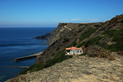 A from the hill at arrifana bay and rocks with a typical portuguese rural building in front