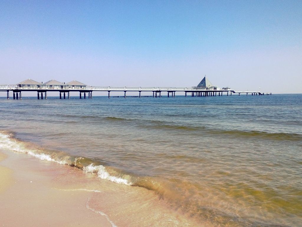 water, sea, clear sky, built structure, architecture, beach, copy space, connection, pier, sand, shore, bridge - man made structure, horizon over water, tranquility, tranquil scene, wave, scenics, nature, travel destinations, beauty in nature