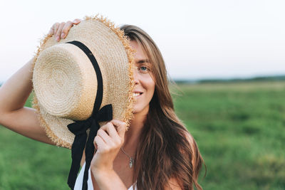  young long hair woman in white dress with straw hat in sunset field. sensitivity to nature concept