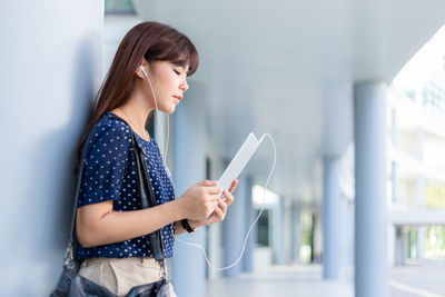 Side view of a young woman using mobile phone