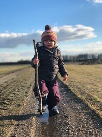 Full length portrait of girl walking on field against sky