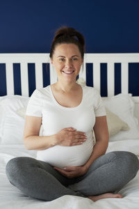 Portrait of smiling young woman sitting on bed