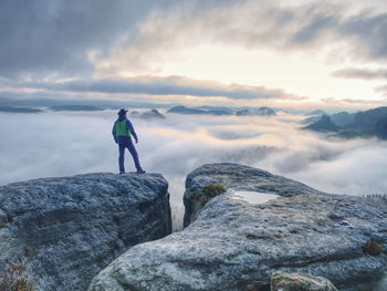 Hike in autumn mountains. man above heavy mist in deep valley. hike in pure nature in all of world