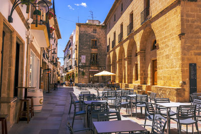 Empty sidewalk cafe amidst buildings in city