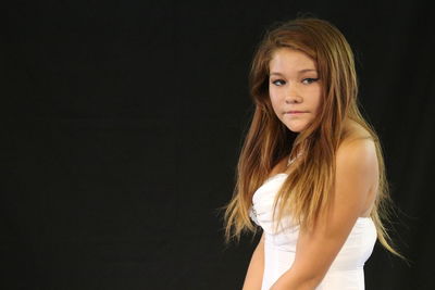 Portrait of girl standing against black background