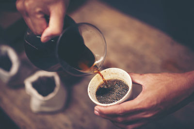 Cropped hand pouring water in coffee cup