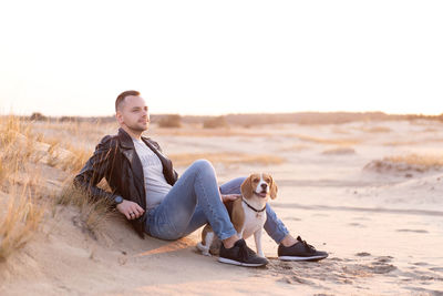 Side view of young man sitting on beach