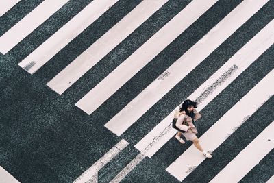 Aerial view of woman crossing zebra