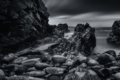 Rocks by sea against sky