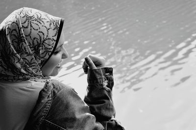 Side view of smiling woman wearing hijab by lake