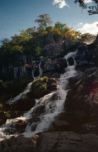 Scenic view of waterfall in forest against sky