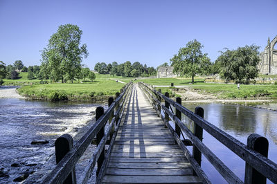 Bridge over calm river against clear sky