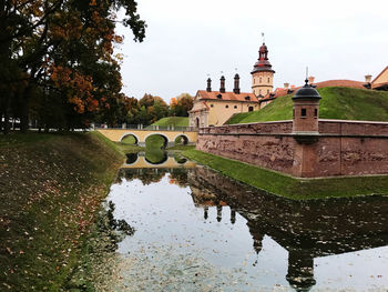 Reflection of building / historical castle and trees in lake against sky in nesviz, belarus heritage 