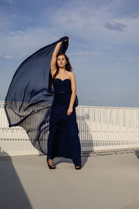 Full length portrait of woman standing against sky