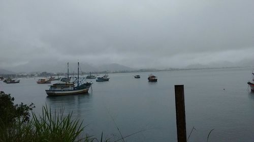 Boats in sea against cloudy sky