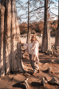 Woman standing by tree trunk