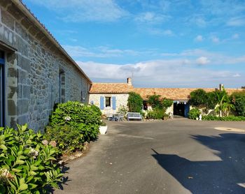 Trees and buildings with yard against sky in countryside 