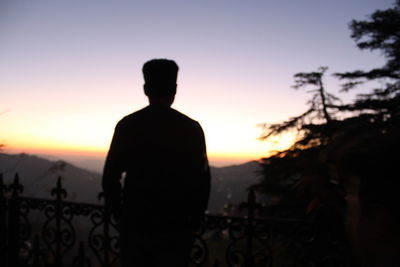 Rear view of silhouette man standing against sky during sunset