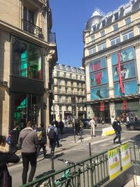 People walking on street against buildings in city