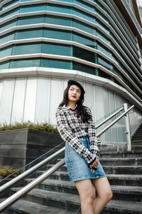 Woman leaning on railing against modern building