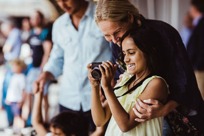 Happy daughter showing camera to mother while standing by family at station