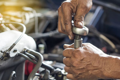 Cropped hands of mechanic repairing car at auto repair shop