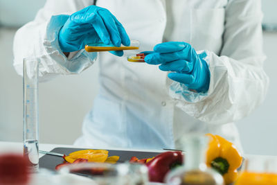 Midsection of scientist experimenting on bell peppers