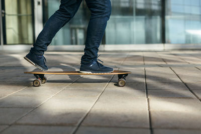 Man skateboarding in city with one foot placed on board and pushing off with the other. 