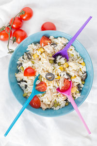 Cold rice salad and three colored spoons.