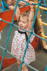 Low angle view of girl playing on rope in playground