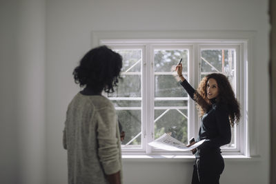 Side view of young woman standing against wall