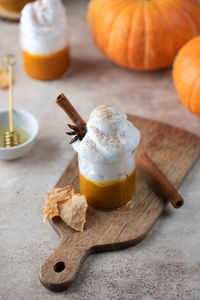 Pumpkin coffee with whipped cream and spices on table