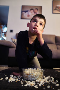 A kid eats popcorn at home while watching a movie