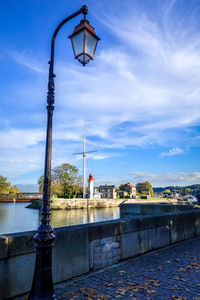 Street light by river against sky
