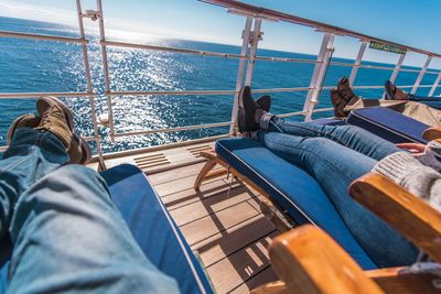 Low section of people relaxing on boat in sea during sunny day