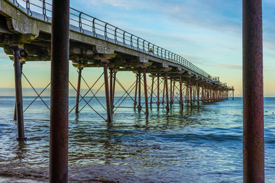 Silhouette bridge over sea against sky