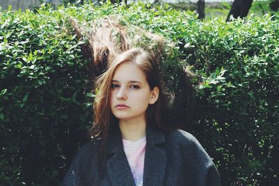 Portrait of beautiful woman against plants at park