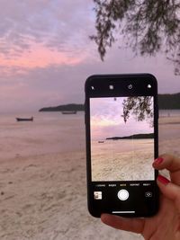 Man photographing on mobile phone at sunset
