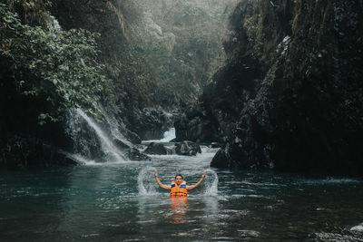 Man surfing in river against trees in forest